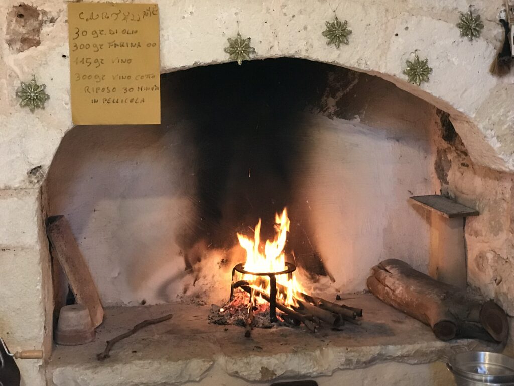 A traditional cartellate recipe over the fireplace in a Puglia masseria. A fire burns in preparation for frying the cartellate. Photo by the Puglia Guys. PugliaGuys.com