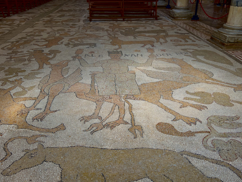 Inside Otranto Cathedral is one of the largest and best preserved medieval floor mosaics in Europe. The mosaic, which spans the length of the central nave and parts of the side naves, consists of around 10 million individual tiles. It was completed in only three years, in 1166, by the monk Pantaleone of San Nicola di Casole monastery.

Depicting the Tree of Life, three allegorical trees serve as an ancient Wikipedia, encompassing themes from the Holy Scriptures such as Genesis, the Flood, Solomon and the Queen of Sheba, and scenes of Heaven and Hell. The mosaic includes representations of Ancient Roman bestiarii, months of the year, and mythological figures like Atlas with the globe on his shoulders. There are depictions from classical and Breton legends: Alexander the Great’s ascent to the heavens and King Arthur. This synthesis of Greek, Byzantine, and Norman cultural themes reflects Otranto’s cultural diversity, where Christianity and Judaism coexisted. The city hosted a vibrant Jewish community of 500 families in the 12th century.

Photo by the Puglia Guys, Puglia ambassadors. PugliaGuys.com